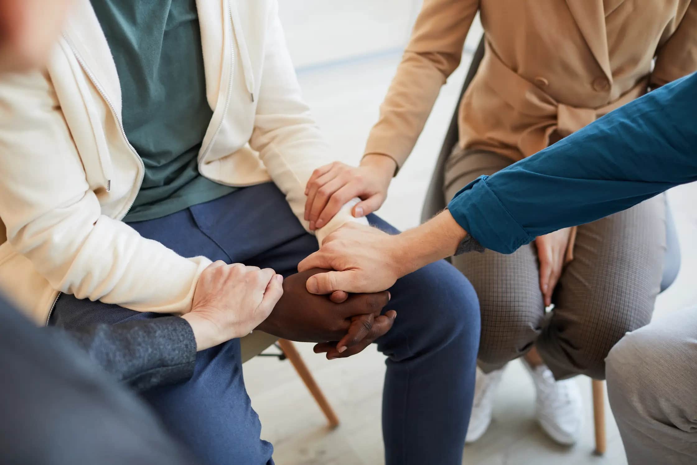 A support group sitting together with hands joined